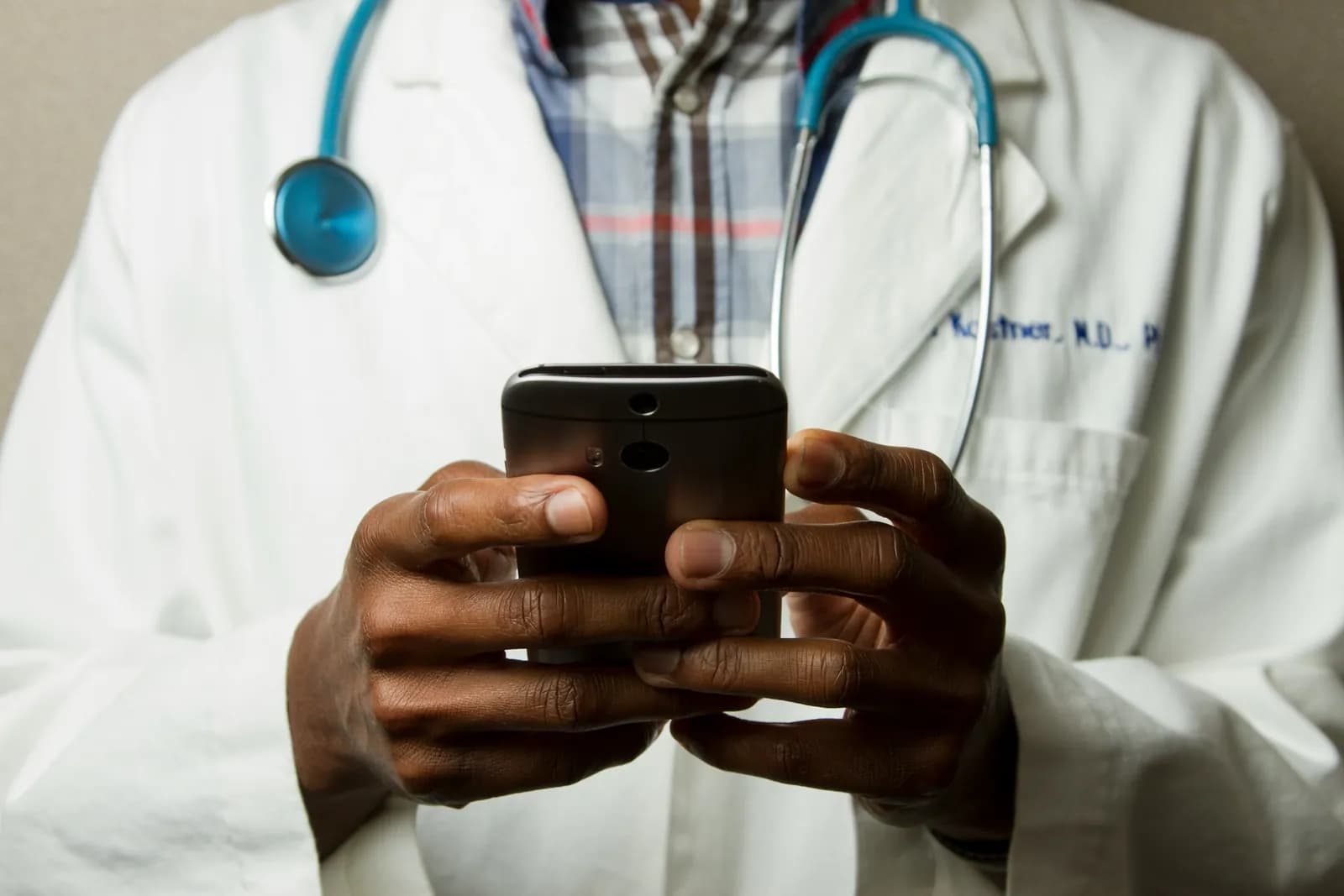 Doctor in a white coat with a stethoscope using a smartphone